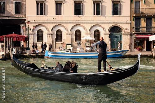October 16, 2019, Venice, Italy: A gondola carrier takes a tourist along the Grand Canal, with a building and vacationers in the background © Serhii