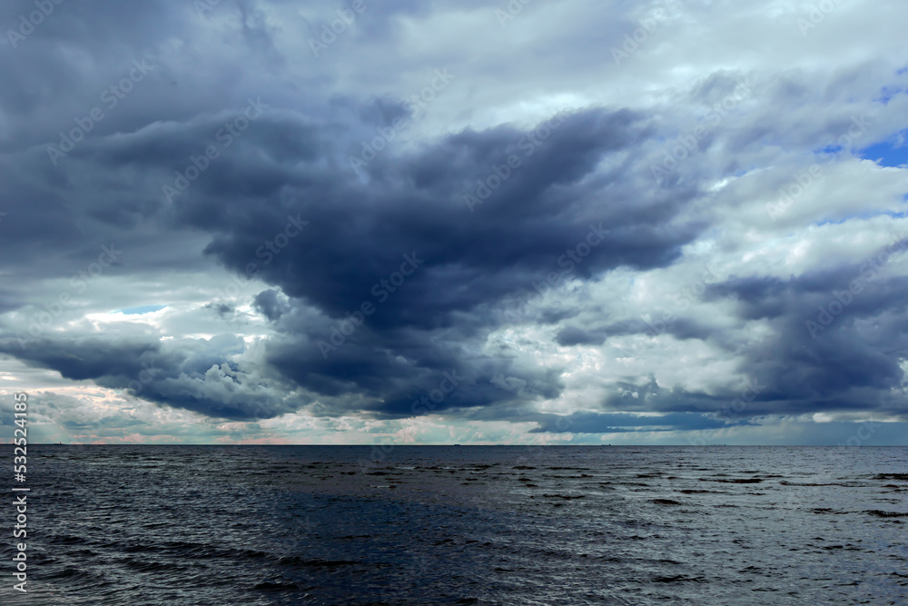 Fototapeta premium Dramatic stormy dark cloudy sky over Baltic sea just before a sea storm in Riga, Latvia. Nature environment concept. Gloomy and moody background.