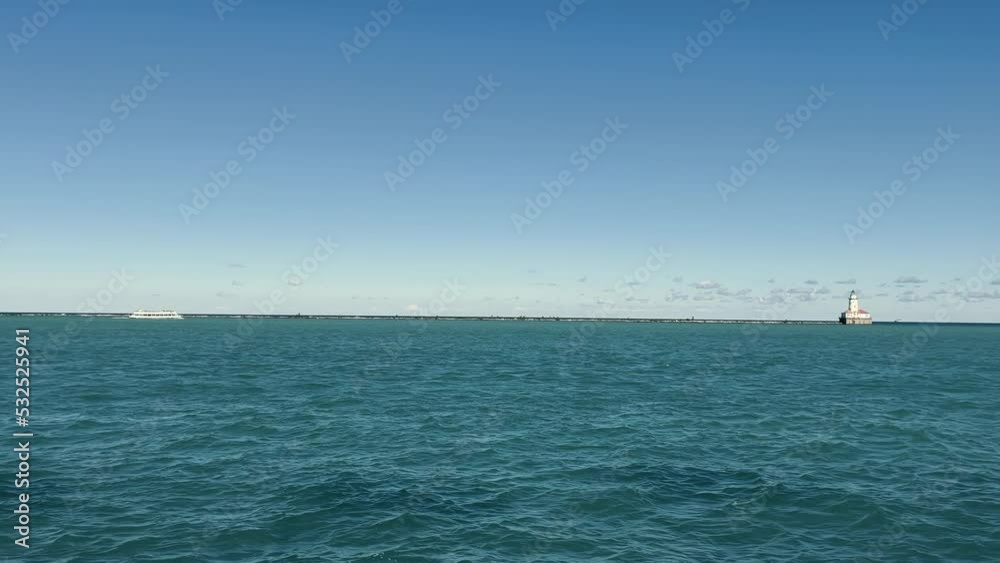 Lake Michigan landscape and a small lighthouse on the horizon. Big lake and landscape in the day. Cloudless blue sky. The static shot is shot from the hands. Lake Michigan landscape and a small lighthouse on the horizon. Big lake and landscape in the day. Cloudless blue sky. The static shot is shot from the hands.