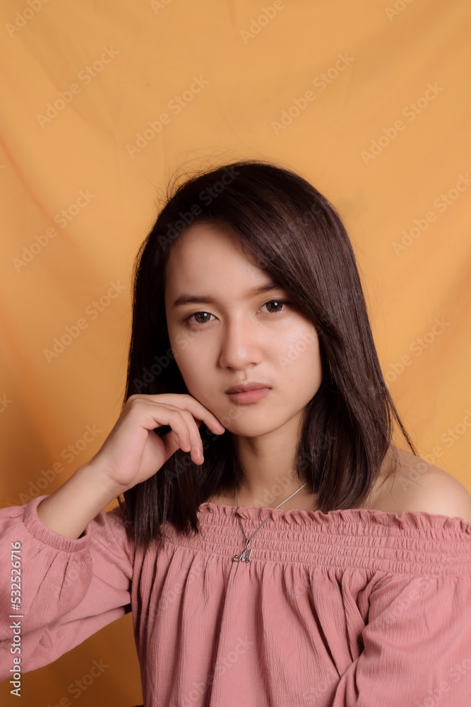 Young Asian woman wearing a pink crop top. Stand up and take half the body on a yellow background. Express emotions. Young Asian woman wearing a pink crop top. Stand up and take half the body on a yellow background. Express emotions.