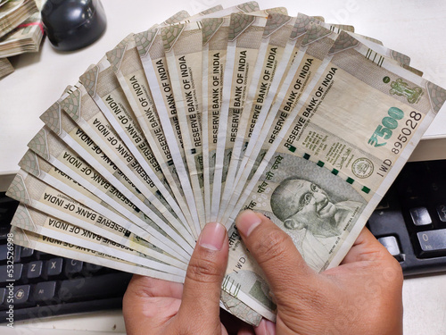 A lot of 500 hundred rupee Cash or bank notes hold by man like playing cards