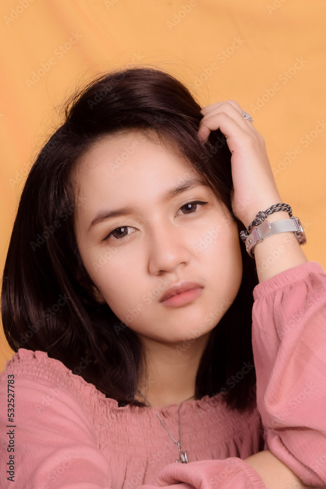 Young Asian woman wearing a pink crop top. Stand up and take half the body on a yellow background. Express emotions. Young Asian woman wearing a pink crop top. Stand up and take half the body on a yellow background. Express emotions.