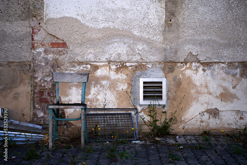 Old chair against the old worn wall of destroyed house photo