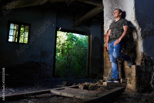 Mature man in a ruined barn and house