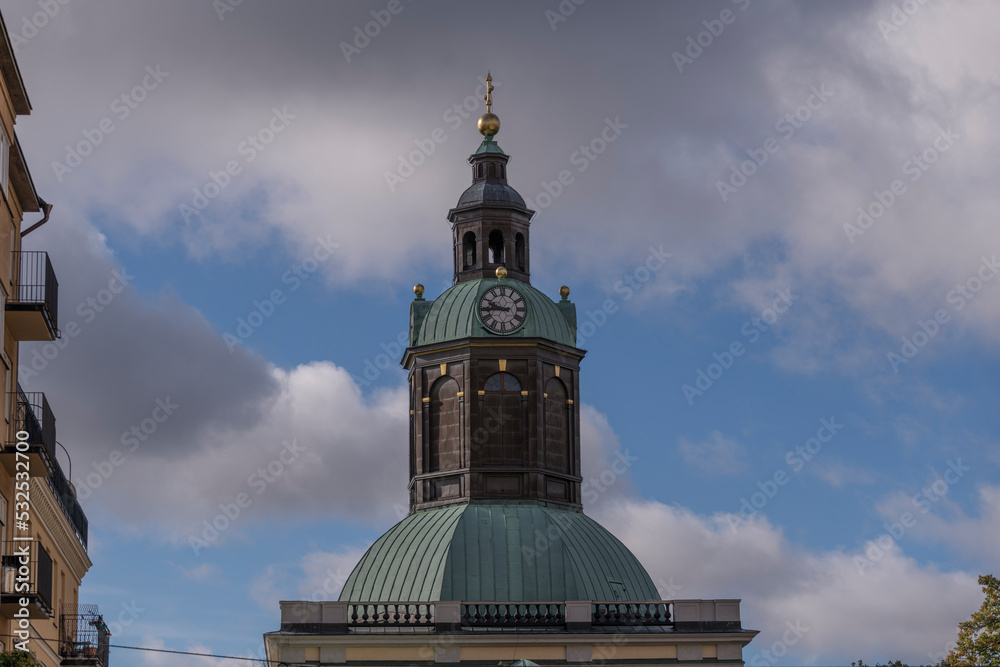 The clock tower of the church Kungsholms kyrka and cumulus clouds an autumn day in Stockholm