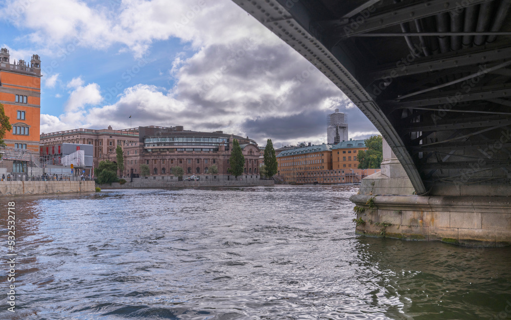 The bridge Vasabron arch fundament and the Swedish Parliament on the island Helgeandsholmen in the stream Norrström with troubled water a cloudy autumn day in Stockholm 