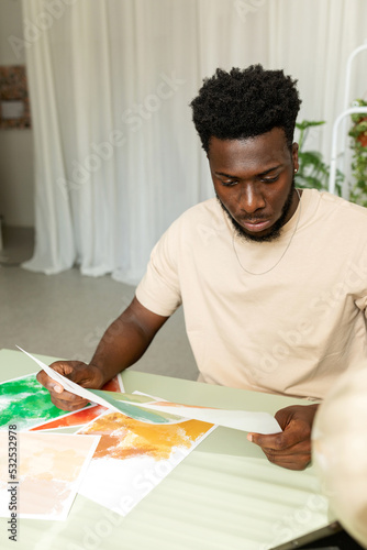 Creative black man selecting abstract designs in workspace