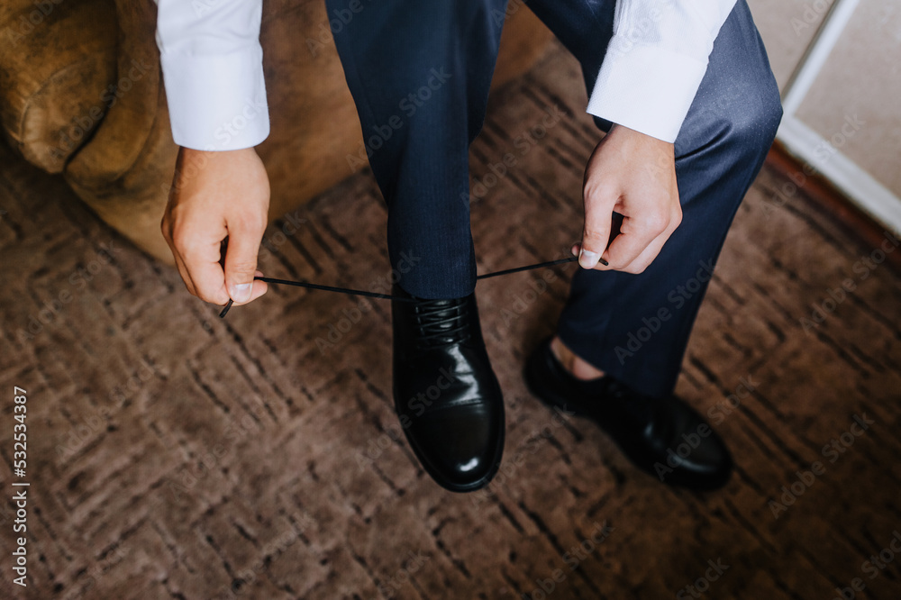 Man, groom, businessman tying shoelaces on black leather shoes. Photography, business.