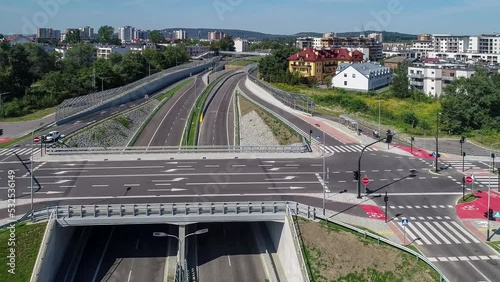 End/Begenning of new city highway Trasa Lagiewnicka in Krakow, Poland, with slip roads, noise barriers, multilevel junction, viaduct for pedestrians and bikes. Aerial approaching video
 photo