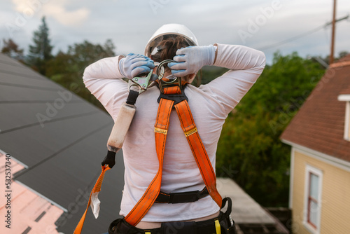 Roofer woman from back putting on harness safety