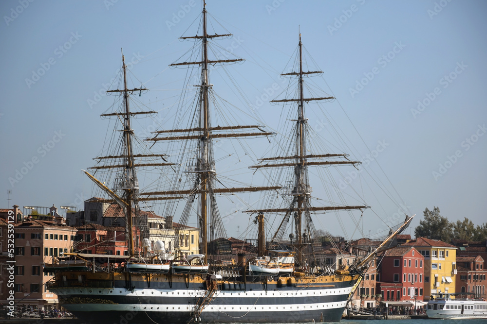 An ancient large ship stands near the pier in the port against the background of old low-rise buildings An ancient large ship stands near the pier in the port against the background of old low-rise buildings