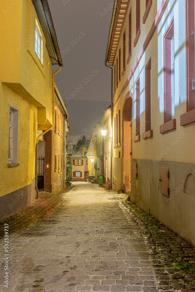 illuminated small alley in a small german town on a cold winter night with thin layer of snow.