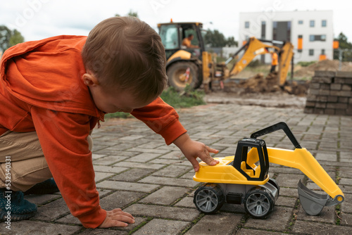 Φωτογραφία Child with excavator near construction site, dreams to be an engineer