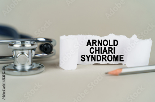 On a gray background, a stethoscope, a pencil and a paper plate with the inscription - Arnold chiari syndrome