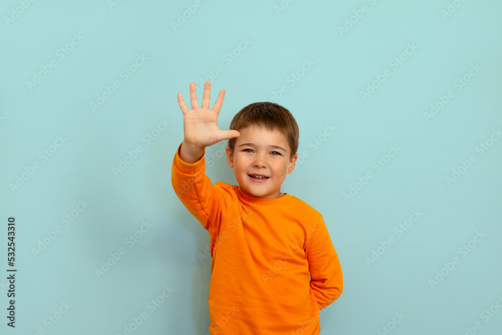 child boy showing five fingers on blue background copy space. portrait of a 5 year old boy child boy showing five fingers on blue background copy space. portrait of a 5 year old boy