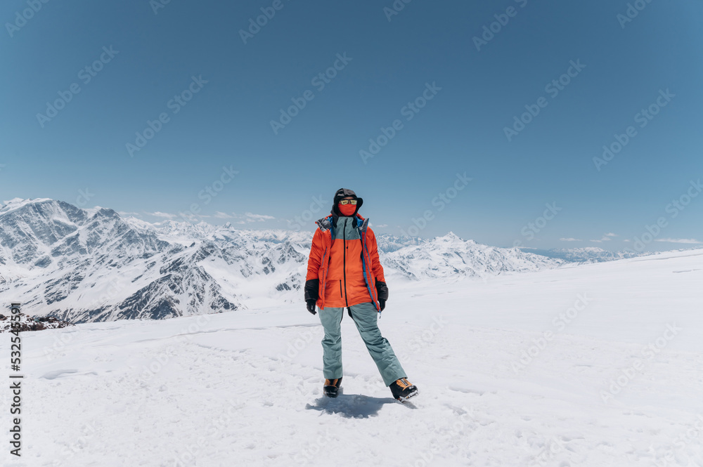 Hiker in warm clothes standing on snowy mountain slope Hiker in warm clothes standing on snowy mountain slope