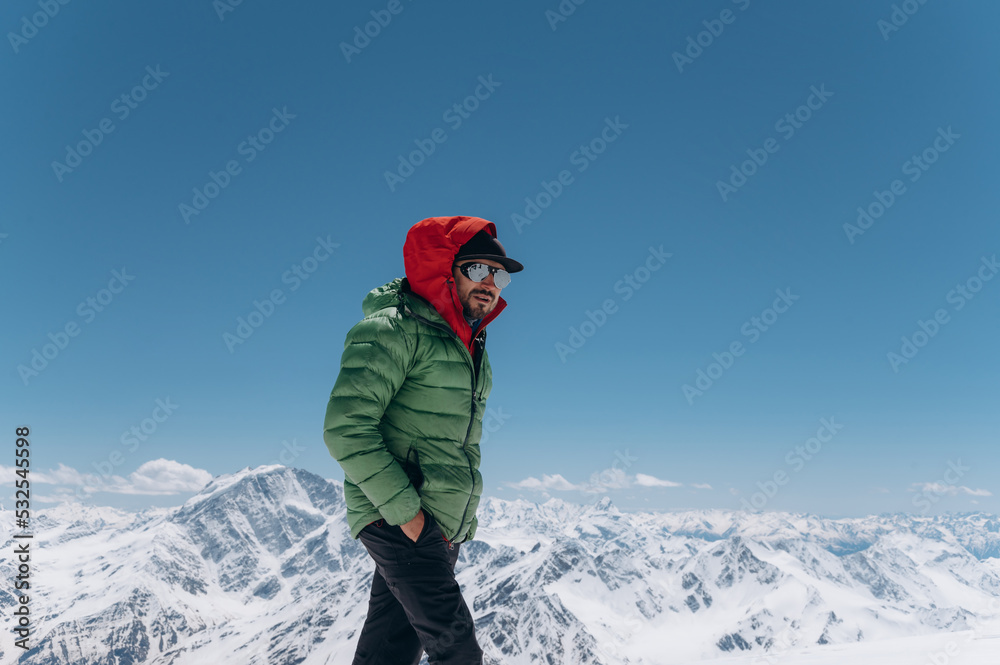Male traveler standing on snowy mountain top in winter Male traveler standing on snowy mountain top in winter