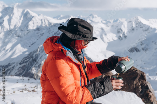 Woman pouring tea in snowy mountains photo