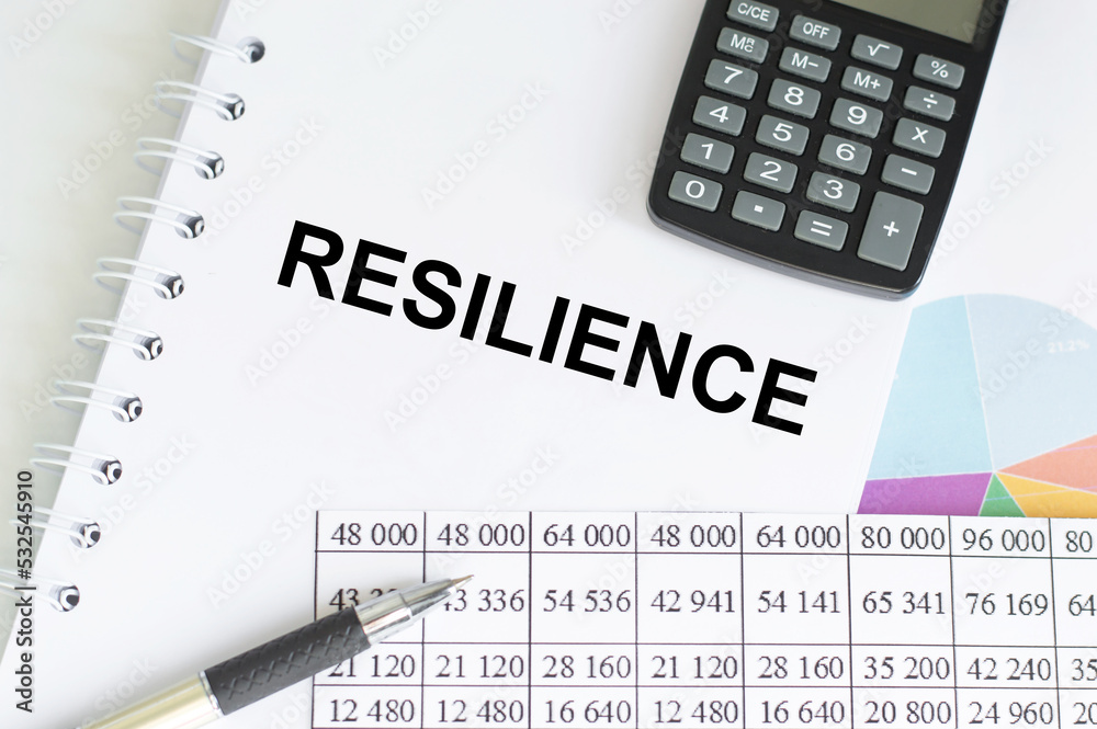 resilience writing on a notepad on a desk among reports and a calculator, pen resilience writing on a notepad on a desk among reports and a calculator, pen