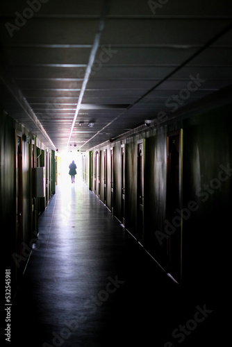 Woman walking alone in the dark. Woman, in a dark, long corridor, defocused