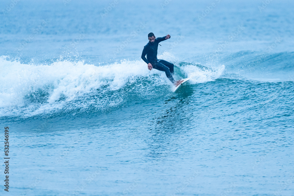 Surfer riding a wave with on a foggy morning in Furadouro beach, Ovar - Portugal. Surfer riding a wave with on a foggy morning in Furadouro beach, Ovar - Portugal.