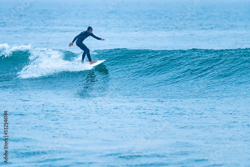 Surfer riding a wave with on a foggy morning in Furadouro beach, Ovar - Portugal.