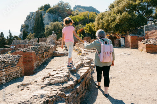 Kid and woman walking on ancient Greek ruines in Taormina, Sicily photo