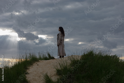 woman in a trench coat against the sky photo