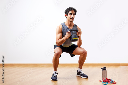 Glad sportsman doing kettlebell goblet squat