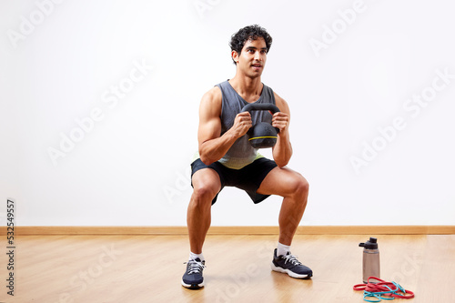 Glad sportsman doing kettlebell goblet squat photo