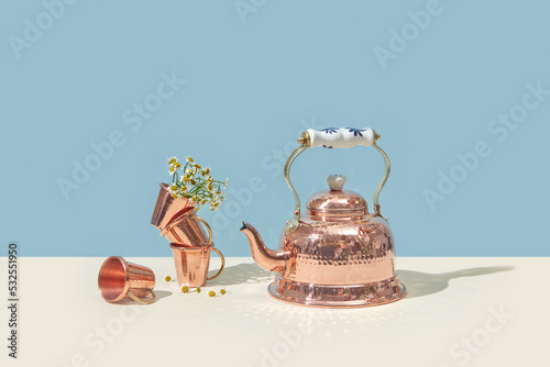 Vintage copper kettle and cups with chamomile flowers. photo