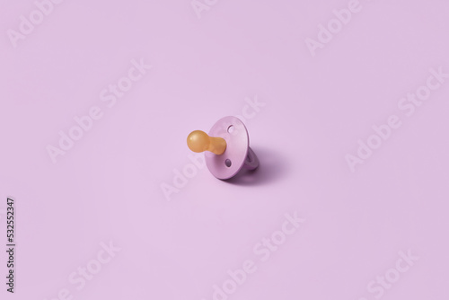 Single pacifier on pink background.