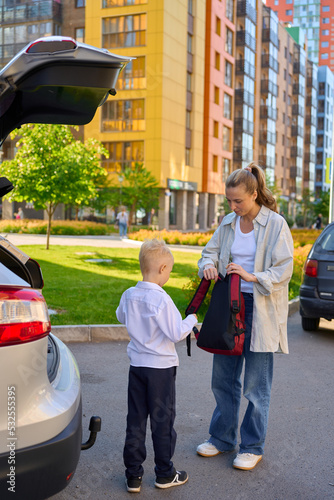 mother with a schoolboy child is standing near the car with a backpa photo