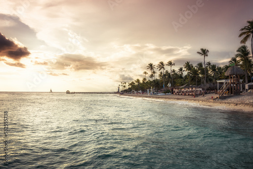 Beach sea palm trees sunset sea surf waves tourists resort coastline scenery with dramatic sunset sky as tropical island background  photo