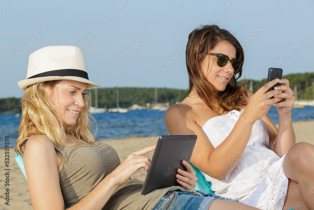 women using gadgets while on the beach