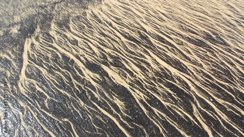 TEXTURA CREADA POR EL ALQUITRÁN EN LA ARENA DE  LA PLAYA. BREA Y ARENA. CONTAMINACIÓN.