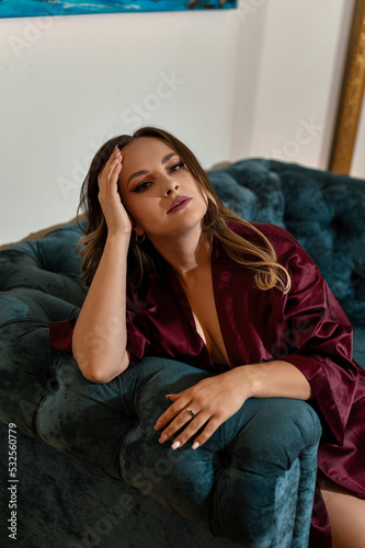 a girl in a marsala-colored bathrobe poses erotically in underwear in a hotel in a French-style apartment against the background of mirrors on a blue sofa candles