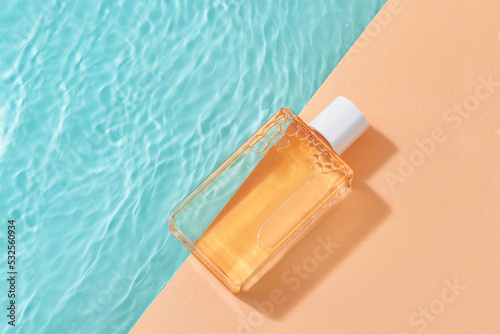 Bottle of cosmetic product near swimming pool photo