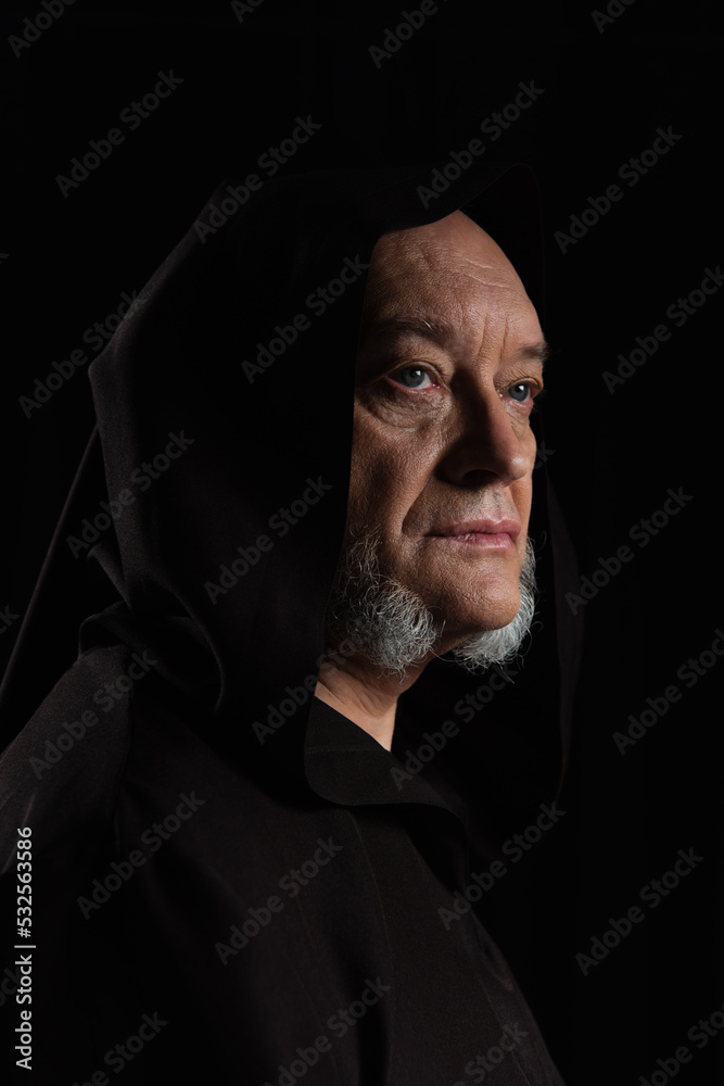 portrait of medieval monk in hooded robe isolated on black.