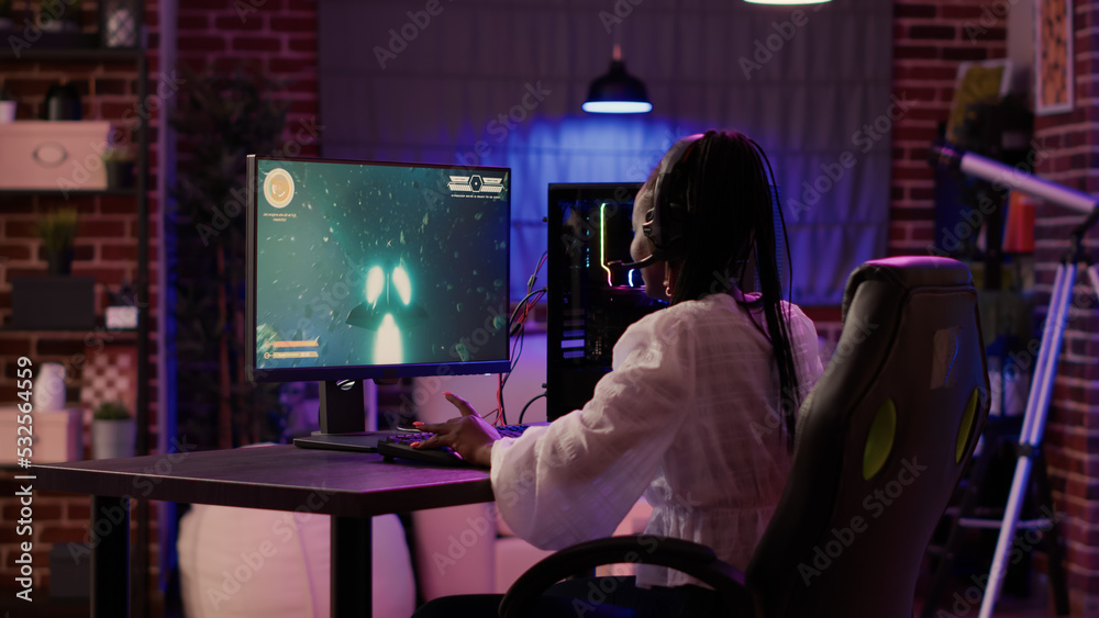 Woman playing multiplayer space shooter simulation enjoying free time using pc  gaming setup in home living room. African american gamer girl talking in  headset while streaming online action game. Photos | Adobe