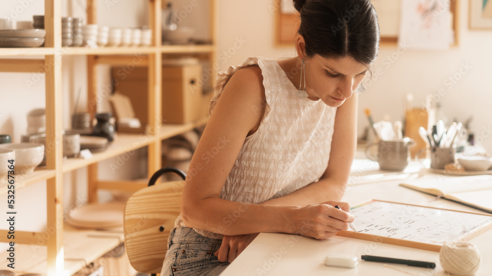 Female Entrepreneur Working At The Desk In The Ceramics Shop Female Entrepreneur Working At The Desk In The Ceramics Shop