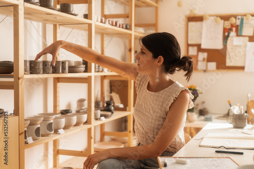 Female Shop Owner Arranging Products In The Ceramics Shop photo