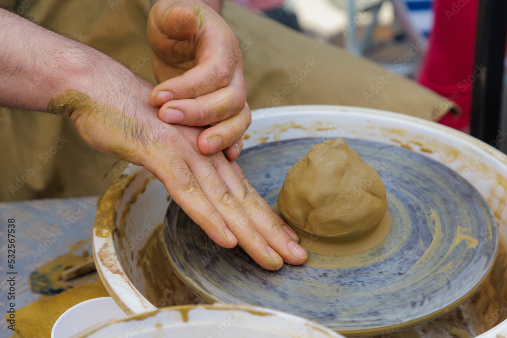 Potter in the process of working on a potters wheel. Close-up hands. Background with copy space