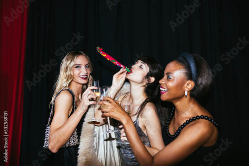 Trendy ladies clinking champagne glasses during party