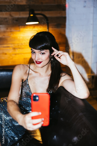 Alluring female smiling and taking selfie during eve