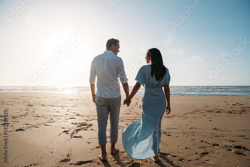 Anonymous couple walking on seashore near sea