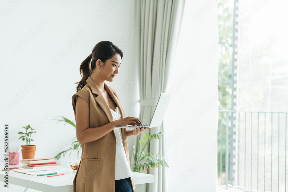 Smiling Asian businesswoman holding a laptop computer Smiling Asian businesswoman holding a laptop computer