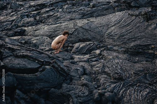 Nude woman sitting on black solid lava in Iceland  photo