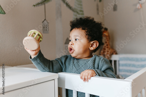 A little boy playing in his crib with a wooden toy / rattle  photo