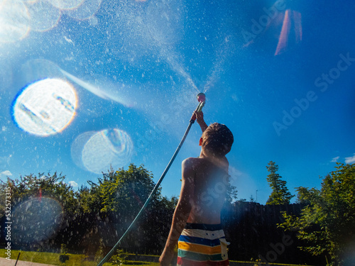 The boy directed a stream of water from the hose into the sky. photo